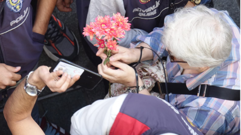 Elinde bir demet çiçek tutan bir hak savunucusunun polis tarafından kuşatıldığını gösteren fotoğraf